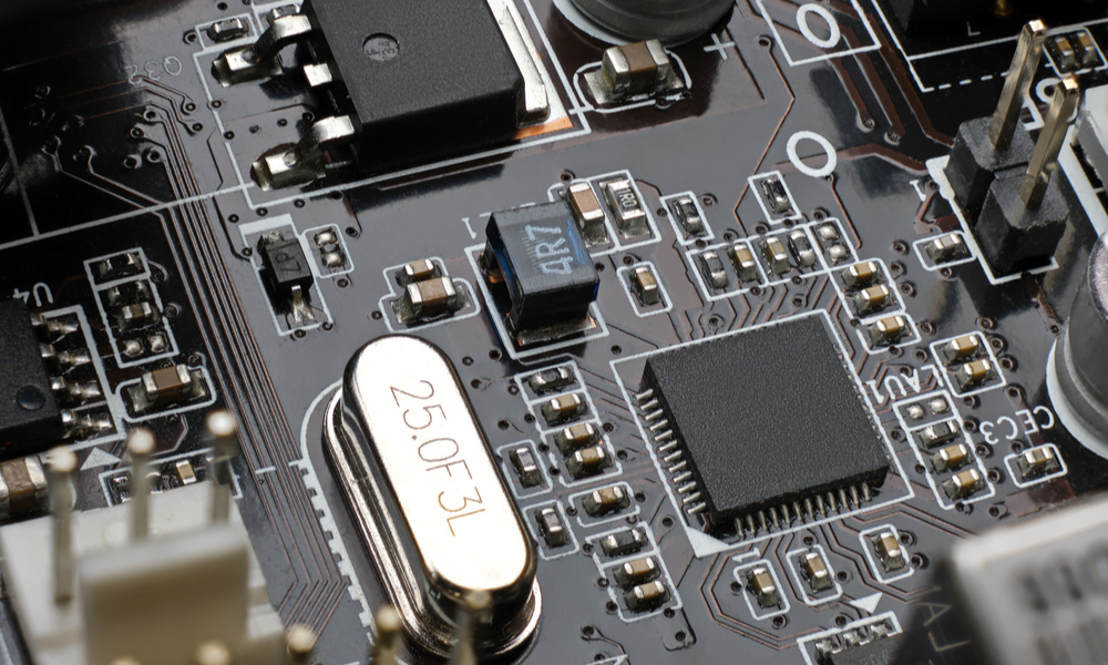 SMD chip Ethernet microcontroller on a brown circuit board, illustrating one of the various types of Crystal Oscillators used in electronic communication systems.