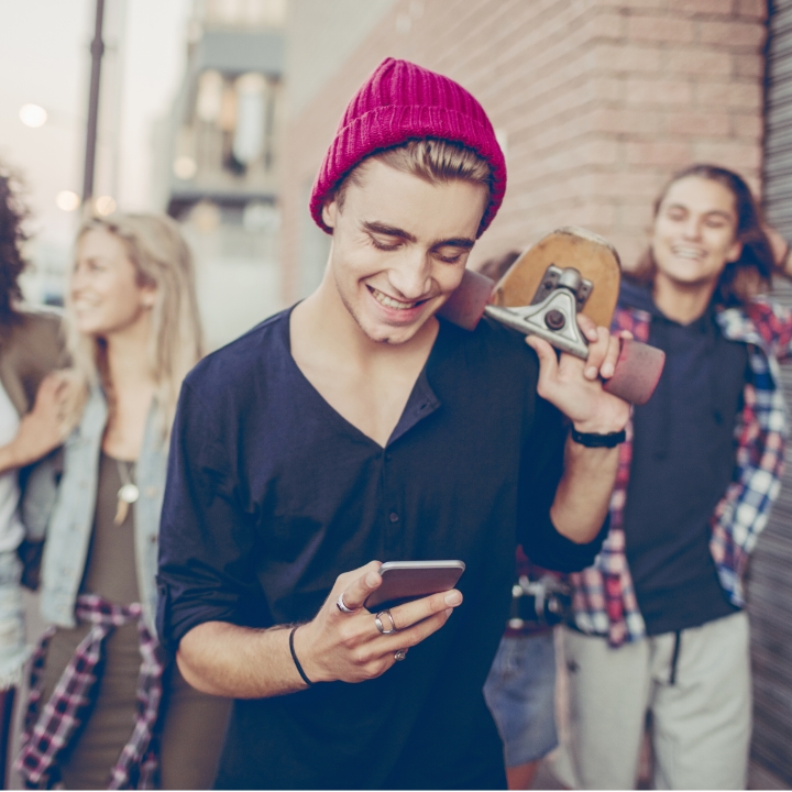 Young man with mobile phone enjoying time with friends